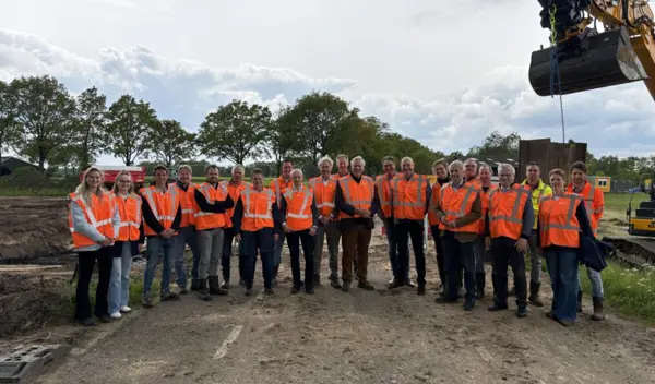 Groepsfoto Projectbezoek DIWA met iedereen gekleed in oranje veiligheidshesjes